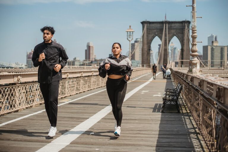 Casal correndo no Brooklyn Bridge em Nova York durante treino ao ar livre, praticando atividade física para saúde e Bem Estar