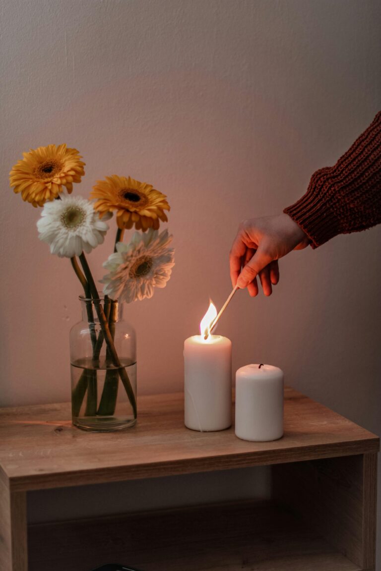 Ambiente aconchegante com flores e vela sendo acesa, representando hábitos para saúde mental que ajudam a relaxar e cuidar do bem-estar diário.